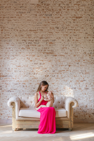 Breastfeeding in front of rustic brick wall. Minimalismの写真素材