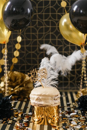 Birthday party cake with golden and black decor various balloons. Happy birthday signの写真素材