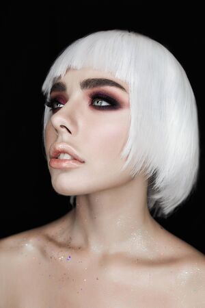 Blonde young woman with fashionable makeup isolated on black background.の写真素材