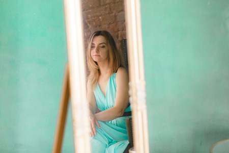 Woman reflection in mirror on green wall isolated with copyspaceの写真素材