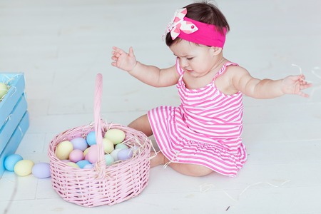 Cute little girl in red dress with Easter eggs sitting on floor at homeの写真素材
