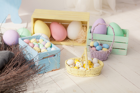 Multicolored easter eggs and in basket and wooden boxes on floorの写真素材