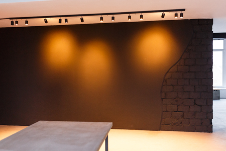 Black office wall with spot light on. Loft style. Concrete table in frontの写真素材