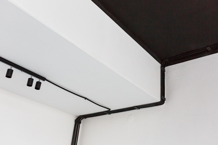 Wiring harness of black corrugated tubes on white wall, goes to spot led lightsの写真素材