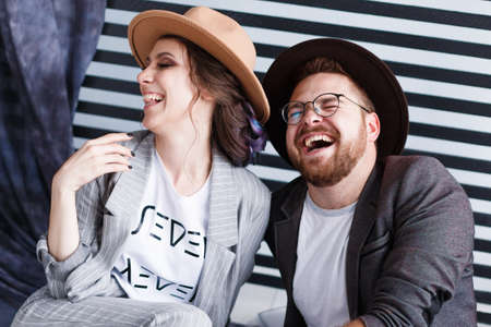 Young happy couple sitting on the floor in their flat isolated on striped background in studioの写真素材