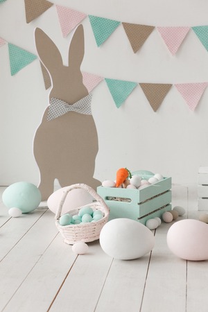 Easter still-life with eggs, carrots bunny paper silhouette and garland on wall. Copy space backgroundの写真素材