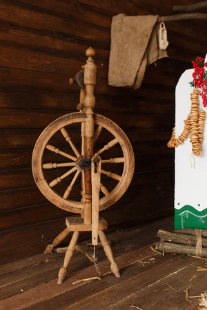 Old wooden spinning yarn wheel in traditional ukrainian interior. Russian folk artの写真素材