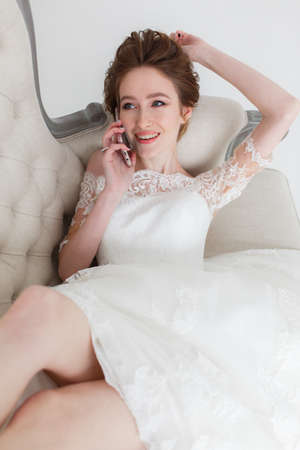 Tender bride talking over cell phone lying on the couchの写真素材