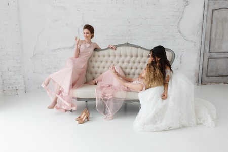 brides taking selfie while playing on sofa and drinking champagneの写真素材