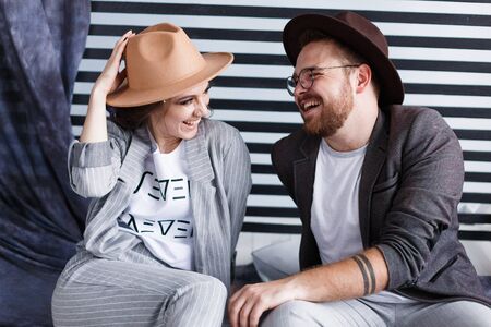 Young happy couple sitting on the floor in their flat isolated on striped background in studioの写真素材