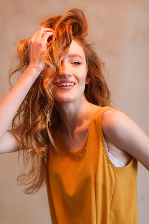 Portrait of beautiful young woman touching her hair. Redhair long hairstyleの写真素材