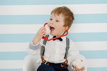 Little Boy with Toy Stethoscope Eating Marshmallowの写真素材