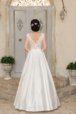 Young bride in white silk wedding dress. Full-lenght vertical portrait.の写真素材