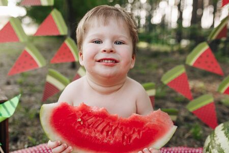 Happy little baby boy eating watermelon outdoorの写真素材