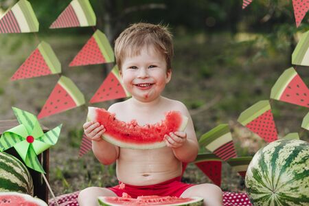 little baby eating watermelon outdoors and smiling making happy faceの写真素材