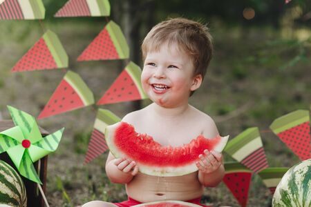 Baby blond boy eat watermelon and smile. Child has healthy eating habitsの写真素材