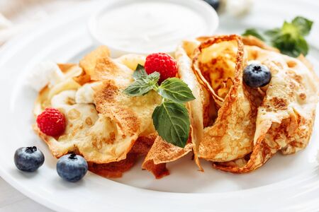 closeup of pancakes with cottage cheeseand strawberry, blueberry on plate on white plate background, decorated with mint leavesの写真素材
