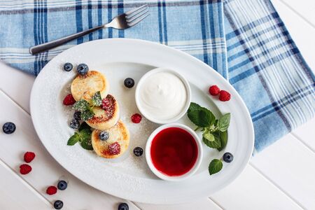 Close cheese pancakes, syrniki, curd fritters with fresh raspberries on white plate background. Top horizontal view.の写真素材