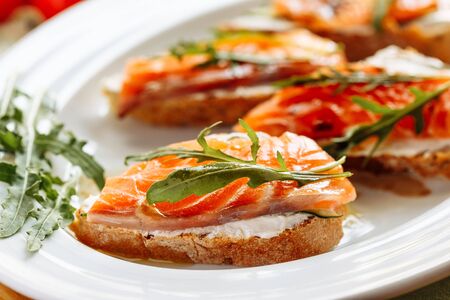 Whole grain bread with avocado paste and salmon decorated with arugulaの写真素材