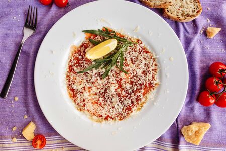 Carpaccio of salmon covered with parmesan, arugula and lemon slice. Top viewの写真素材