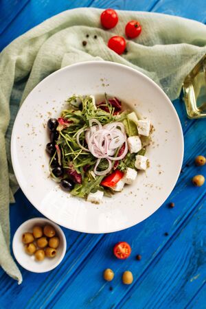 Salad with arugula, tomato, cheese, olives and red onion. Whole plate top vertical viewの写真素材