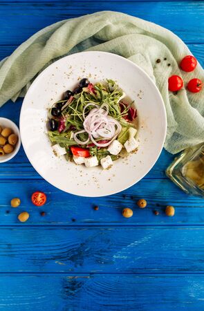 Salad with arugula, tomato, cheese, olives and red onion. Whole plate top vertical viewの写真素材