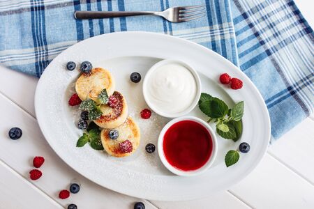 Close cheese pancakes, syrniki, curd fritters with fresh raspberries on white plate background. Top horizontal view.の写真素材
