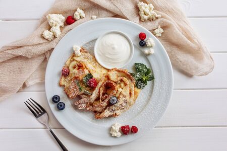 closeup of pancakes with cottage cheeseand strawberry, blueberry on plate on white plate background, decorated with mint leavesの写真素材