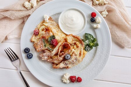 closeup of pancakes with cottage cheeseand strawberry, blueberry on plate on white plate background, decorated with mint leavesの写真素材