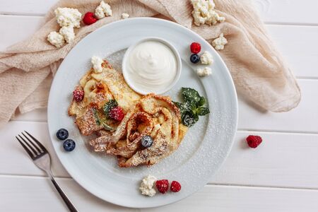closeup of pancakes with cottage cheeseand strawberry, blueberry on plate on white plate background, decorated with mint leavesの写真素材