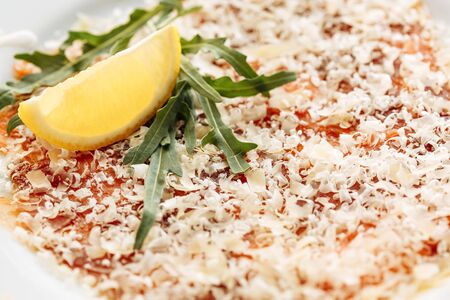 Carpaccio of salmon covered with parmesan, arugula and lemon slice. Close macro viewの写真素材
