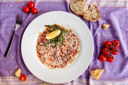 Carpaccio of salmon covered with parmesan, arugula and lemon slice. Top viewの写真素材