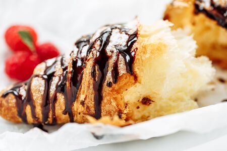Tasty croissant with cream and topping on plate. Close-up shot with tasty fresh texture of liquid chocolateの写真素材