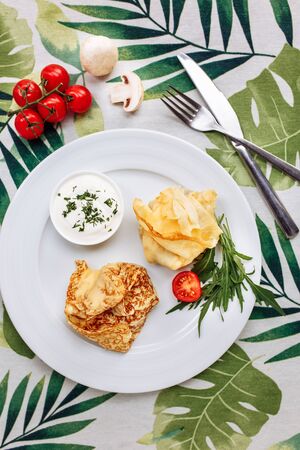 Rolled Delicious Crepes stuffed with chicken and mushrooms on the white plate serving with sour cream. Pancake is a flat cake, often thin and round, prepared from a starch based batter that mayの写真素材