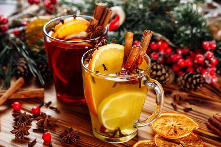 Two glasses of hot mulled wine with oranges and spices on wooden background. Close-up side viewの写真素材