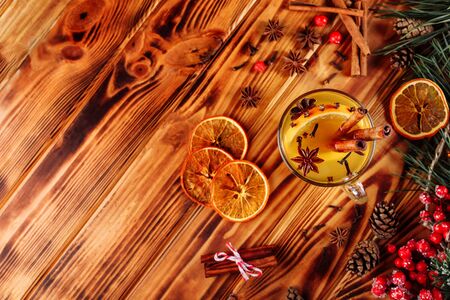One glass cup of christmas mulled wine or gluhwein with spices and orange slices on rustic wooden table top view. Traditional drink on winter holiday. Vintage tonedの写真素材