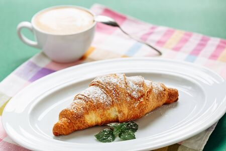 Croissant with coffee cappuccino for breakfast. Side view on cloth napkin backgroundの写真素材