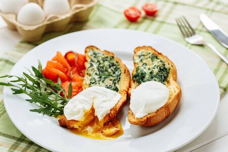 Poached egg on whole wheat toasted croissant with arugula, smoked salmon. Table arrengement side close-up view copy spaceの写真素材