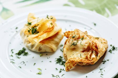 Savory pancake like cake filled with mushrooms and ham on white plate with green dillの写真素材