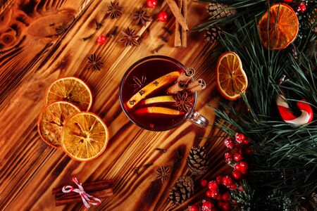 One glass cup of christmas mulled wine or gluhwein with spices and orange slices on rustic wooden table top view. Traditional drink on winter holiday. Vintage tonedの写真素材
