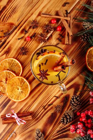 One glass cup of christmas mulled wine or gluhwein with spices and orange slices on rustic wooden table top view. Traditional drink on winter holiday. Vintage tonedの写真素材