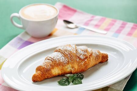 Croissant with coffee cappuccino for breakfast. Side view on cloth napkin backgroundの写真素材