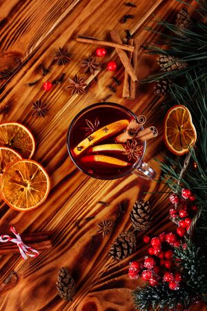 One glass cup of christmas mulled wine or gluhwein with spices and orange slices on rustic wooden table top view. Traditional drink on winter holiday. Vintage tonedの写真素材