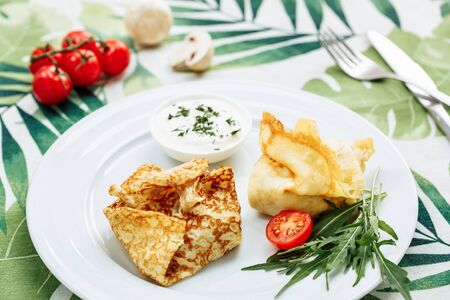 Rolled Delicious Crepes stuffed with chicken and mushrooms on the white plate serving with sour cream. Pancake is a flat cake, often thin and round, prepared from a starch based batter that mayの写真素材