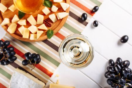 Glass of white wine, Cheese plate with mozarella, parmesan, honey and grapes on table. Top view selective focusの写真素材