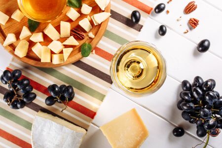 Glass of white wine, Cheese plate with mozarella, parmesan, honey and grapes on table. Top view selective focusの写真素材