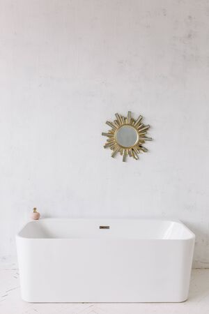 Square frame of modern bathroom with freestanding white bathtub on loft rustic wall background with sun shape mirror hangingの写真素材
