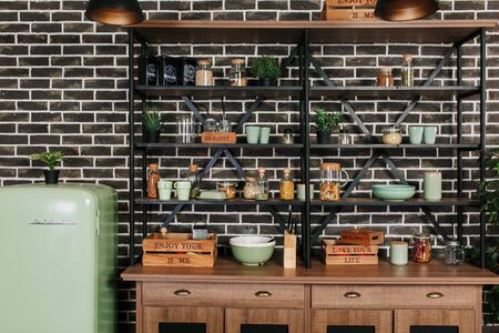 Black loft style storage stand with ceramic and wooden dishware in kitchen. Brick wall backgroundの写真素材