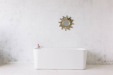 Square frame of modern bathroom with freestanding white bathtub on loft rustic wall background with sun shape mirror hangingの写真素材