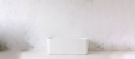 Square frame of modern bathroom with freestanding white bathtub on loft rustic wall background with sun shape mirror hanging. Panoramic blank wall copy spaceの写真素材